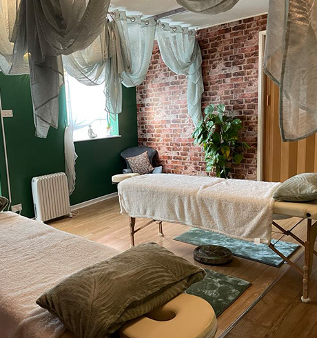 serene massage therapy room with green walls and soft decor featuring two treatment tables and soothing drapes ideal for relaxation and rejuvenation with 9 healing elements