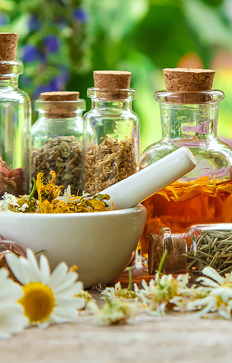 mortar and pestle with dried flowers and herbs surrounded by jars of oils and spices in a natural setting ten herbal remedies for wellness
