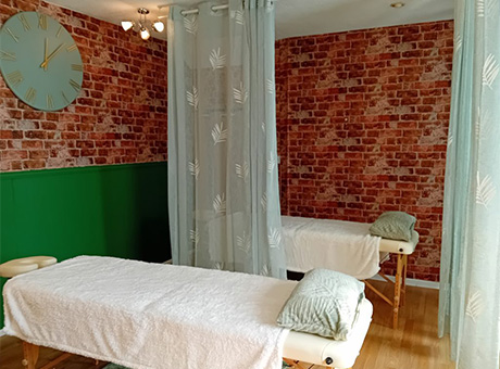 spa treatment room with two massage tables green wall and brick wallpaper relaxing ambiance 6 relaxation techniques 6 wellness options